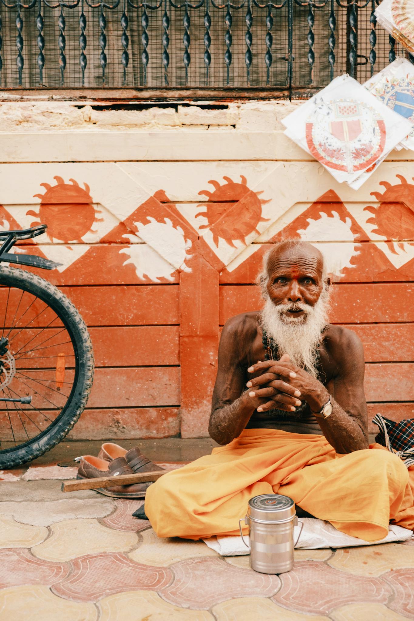 Portrait of an elderly sadhu seated on a vibrant city street in India.